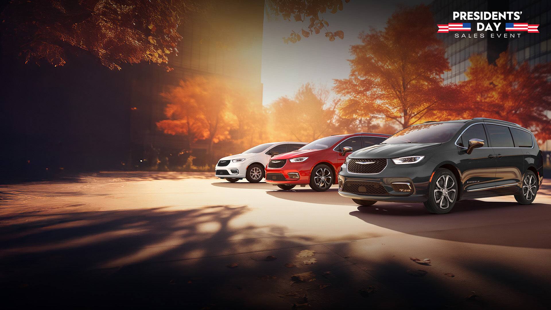 Three 2026 Chrysler minivan models parked on an oceanside beach. From left to right: a white Chrysler Voyager, a blue Pacifica Pinnacle Plug-in Hybrid and a red Pacifica Pinnacle. Presidents' Day Sales Event.