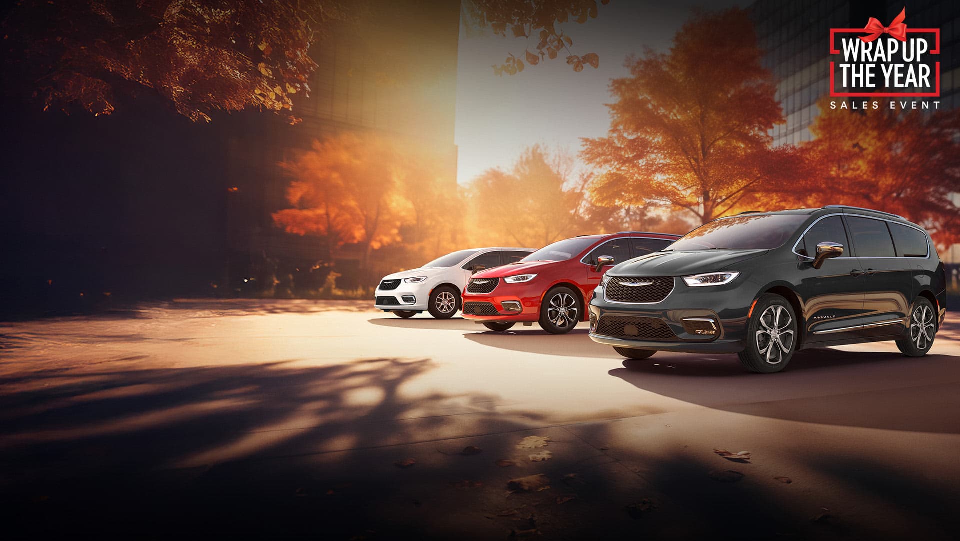 Three 2026 Chrysler minivan models parked on an oceanside beach. From left to right: a white Chrysler Voyager, a blue Pacifica Pinnacle Plug-in Hybrid and a red Pacifica Pinnacle. Wrap Up the Year Sales Event.