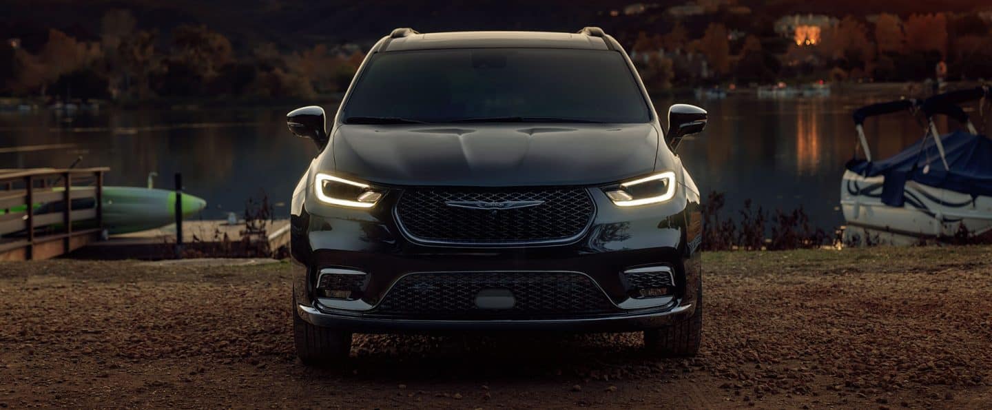 Ángulo frontal de una Chrysler Pacifica Limited 2025 estacionada cerca de un muelle a orillas del agua.