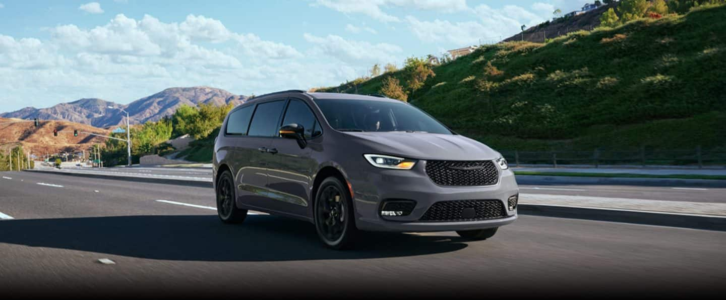 Una Chrysler Pacifica Limited 2025 gris claro circulando por una carretera en las montañas.