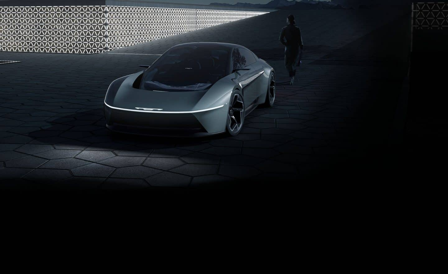 Un ángulo frontal elevado de un vehículo gris Chrysler Halcyon Concept estacionado en un patio oscuro.