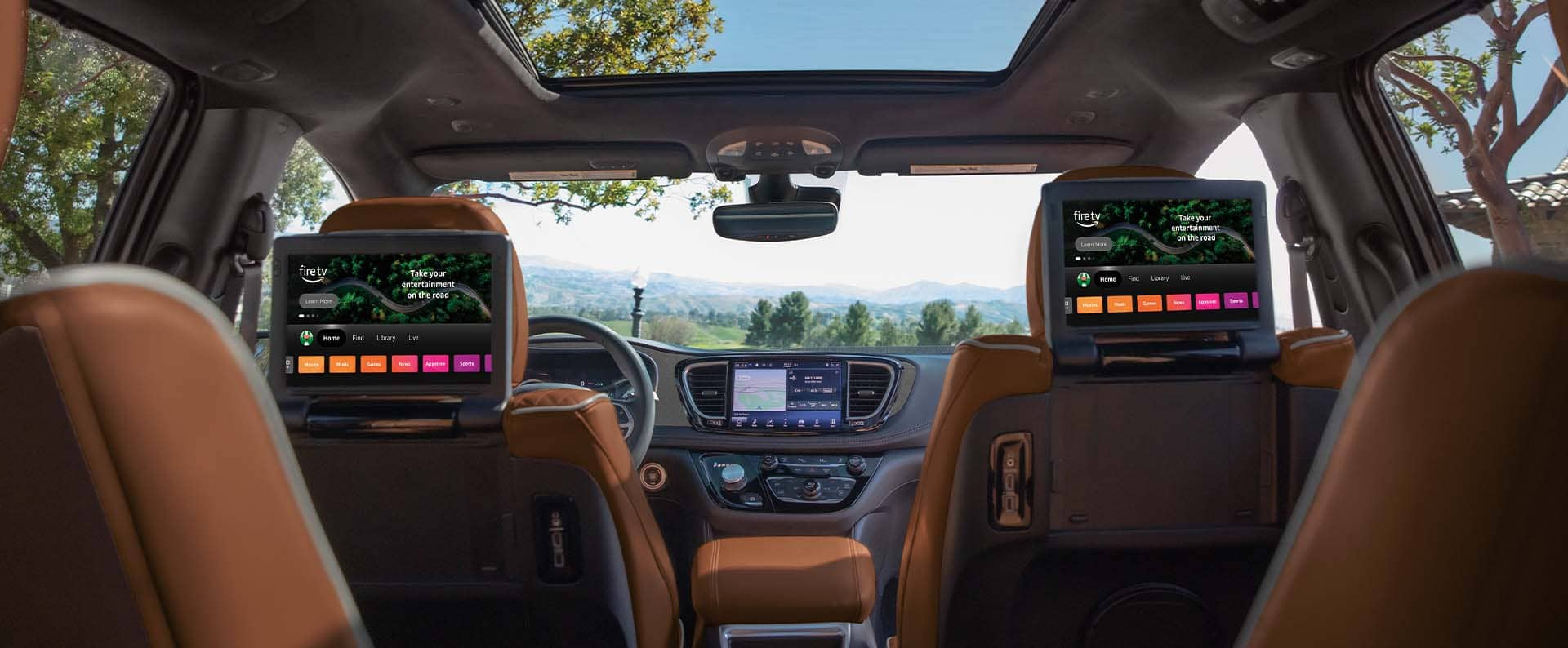 The interior of the 2025 Chrysler Pacifica Pinnacle from the third-row perspective forward, focusing on the dual front seatback-mounted touchscreens for second-row passengers, which are both displaying Amazon FireTV.