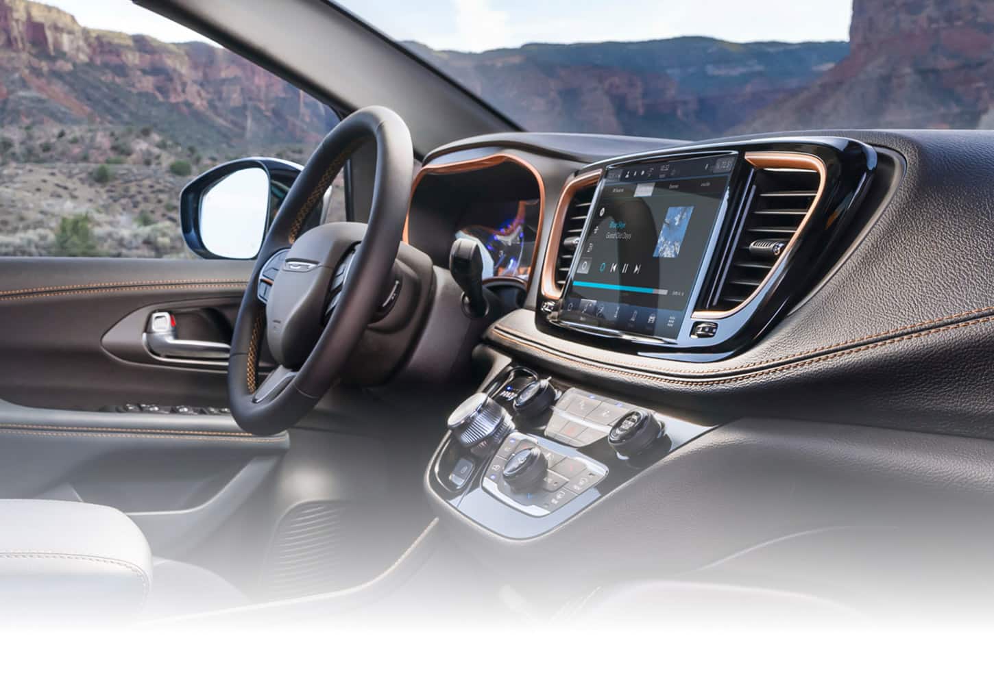 The steering wheel, Uconnect touchscreen and center stack controls in a 2027 Chrysler Pacifica Pinnacle.