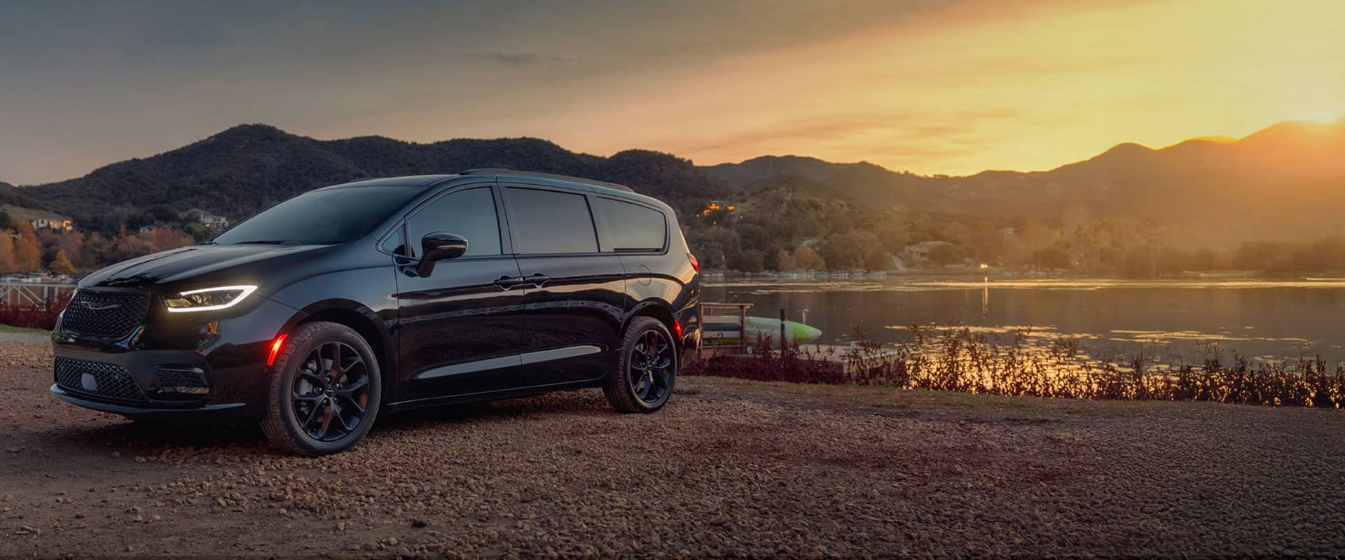 A black 2025 Chrysler Pacifica Limited parked by a lake at sunset.