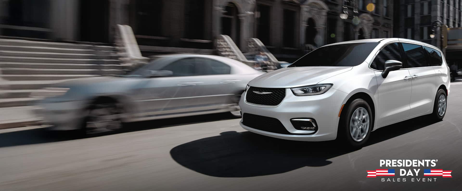 A white 2026 Chrysler Pacifica Select driving down a city street. Presidents' Day Sales Event.