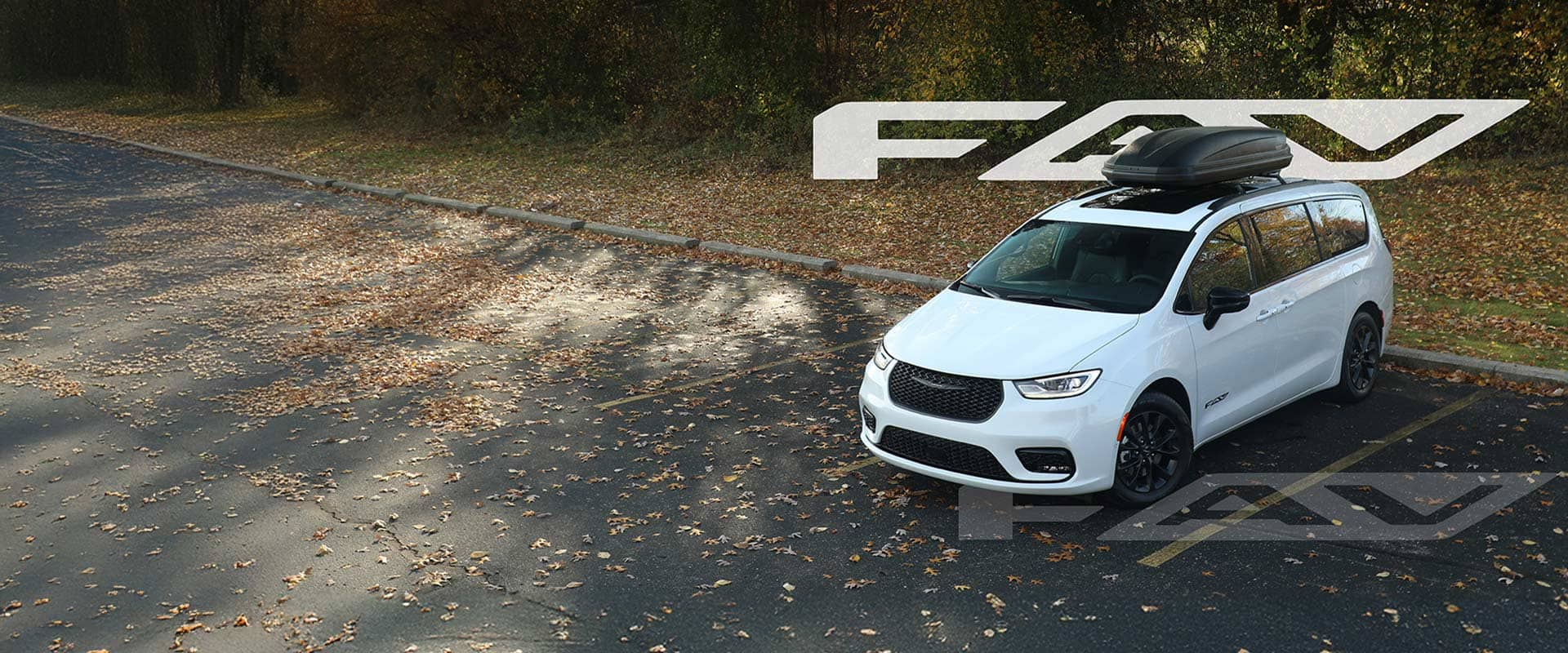 A raised angle of a white 2025 Chrysler Pacifica Select Fav Edition with the black Thule cargo carrier on its roof, parked in a lot at a park in autumn. A large white Fav badge is positioned above and behind the vehicle and a large transparent Fav badge is laid out below the vehicle.