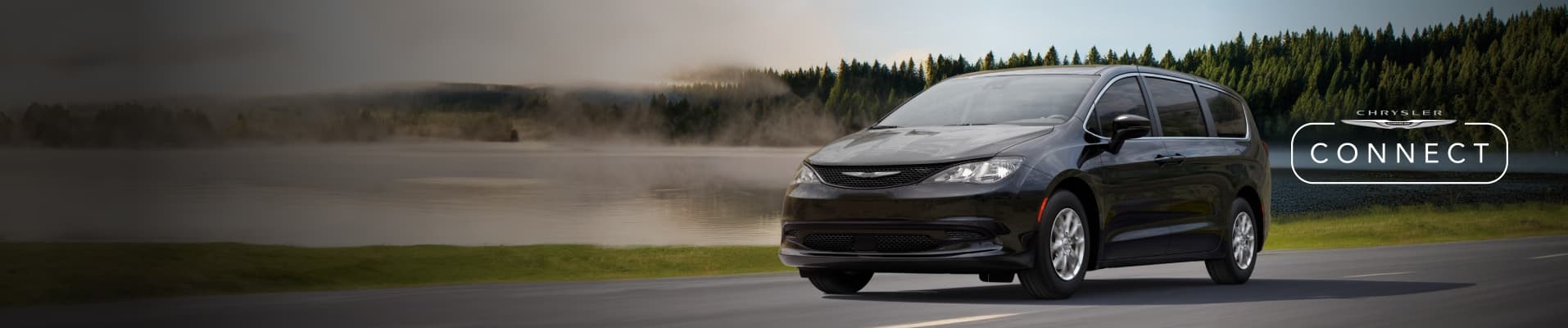 A driver-side front angle of a black 2026 Chrysler Voyager traveling on a highway with a forest in the background. The Chrysler Connect logo.